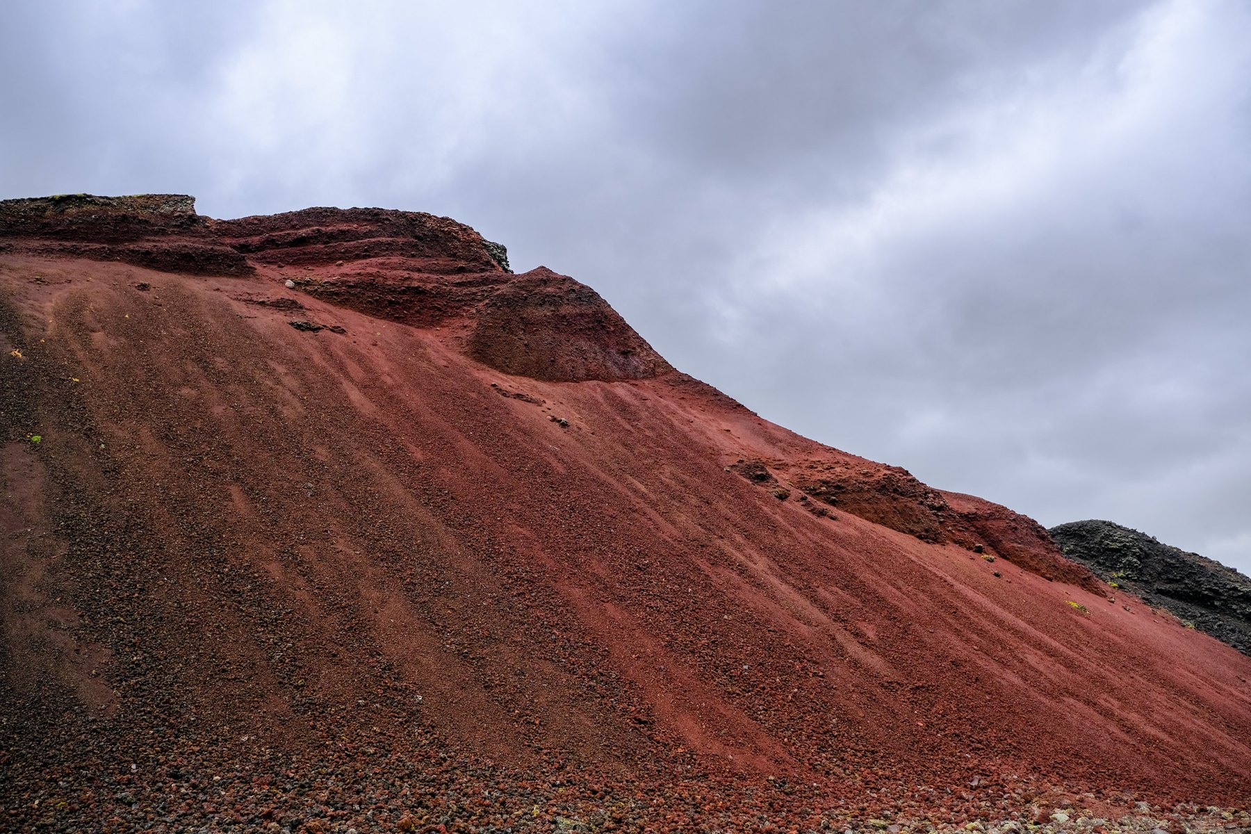Red volcanic hillside under a pale sky.